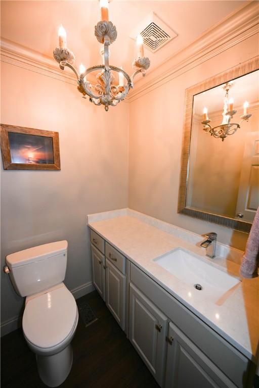 bathroom featuring vanity, toilet, crown molding, and a chandelier