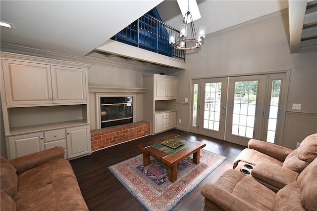 living room with french doors, a brick fireplace, ornamental molding, dark wood-type flooring, and a notable chandelier