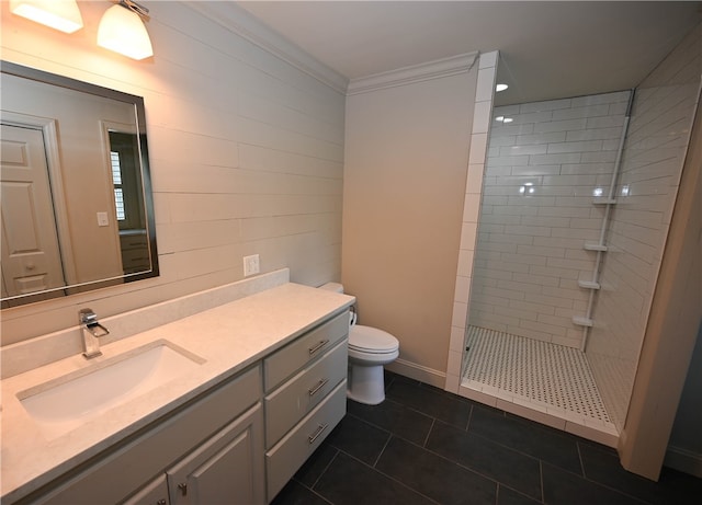 bathroom featuring a tile shower, tile patterned floors, crown molding, toilet, and vanity