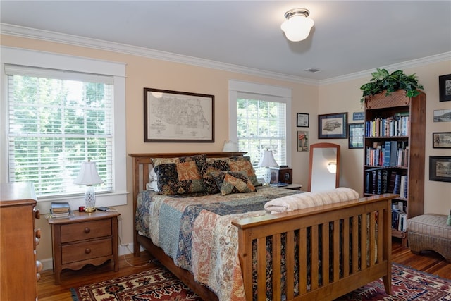 bedroom with multiple windows, wood-type flooring, and ornamental molding