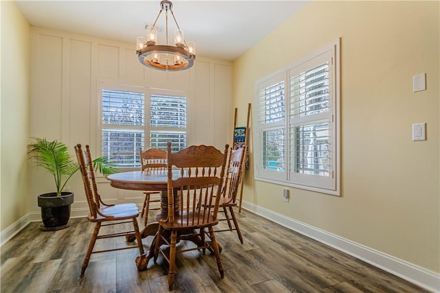 dining space featuring a chandelier, baseboards, and wood finished floors