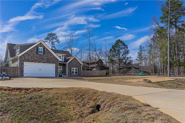 view of front of property with stone siding, concrete driveway, a garage, and fence