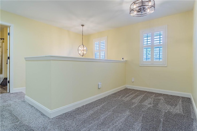 unfurnished room with a notable chandelier, carpet flooring, and baseboards