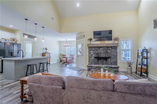 living area featuring a fireplace, wood finished floors, visible vents, and high vaulted ceiling