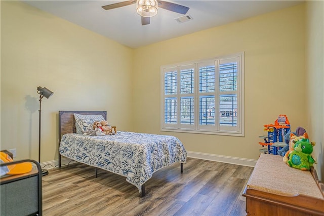 bedroom featuring visible vents, ceiling fan, baseboards, and wood finished floors