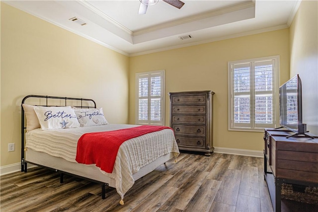 bedroom with a tray ceiling, multiple windows, and visible vents