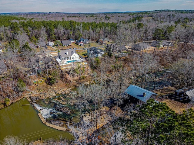 birds eye view of property featuring a forest view and a water view