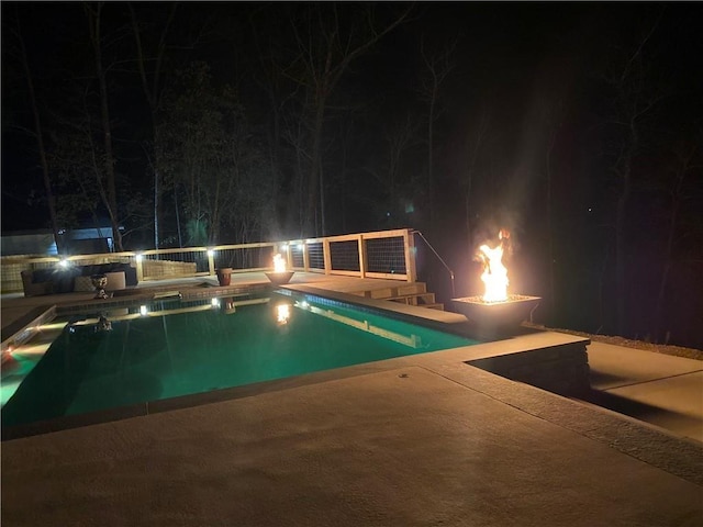 pool at twilight featuring a patio area, an outdoor pool, and a fire pit