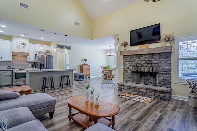 living area with visible vents, high vaulted ceiling, and wood finished floors