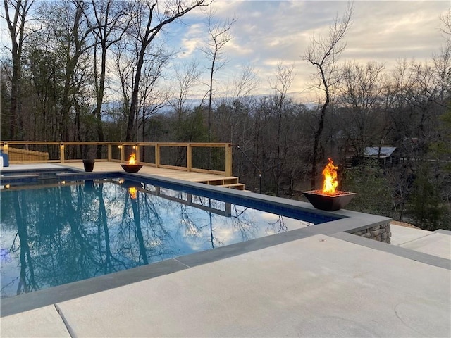 outdoor pool with a wooden deck and an outdoor fire pit