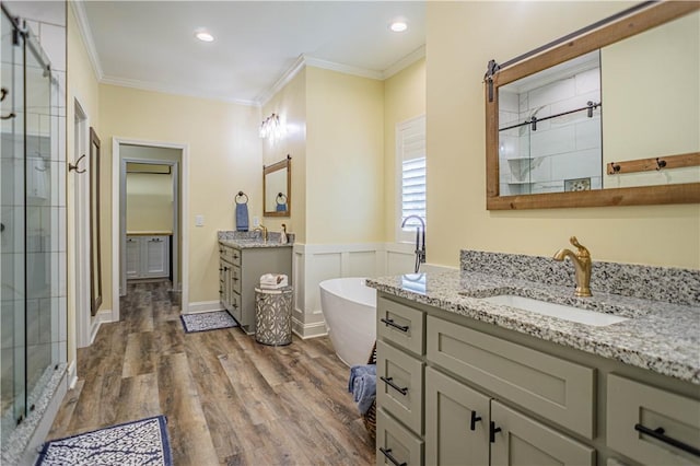 bathroom with wood finished floors, a freestanding tub, a sink, a shower stall, and crown molding