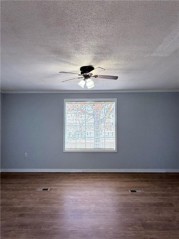 spare room with ceiling fan, ornamental molding, dark wood-type flooring, and a textured ceiling