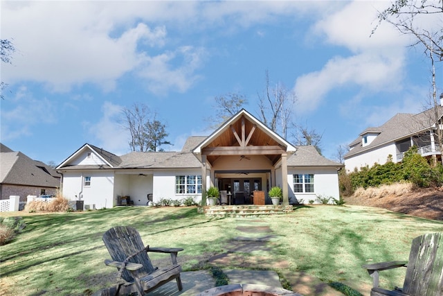 back of property with a yard, a ceiling fan, and stucco siding