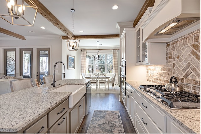 kitchen featuring stainless steel appliances, a sink, custom exhaust hood, tasteful backsplash, and an inviting chandelier