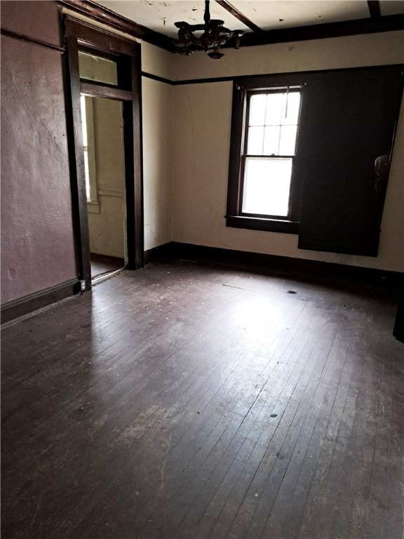 unfurnished room featuring a notable chandelier, baseboards, and hardwood / wood-style flooring