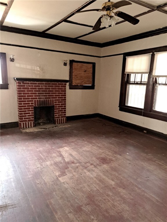 unfurnished living room with a ceiling fan, a brick fireplace, baseboards, and wood finished floors