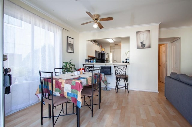 dining room with light wood-type flooring, ceiling fan, baseboards, and crown molding