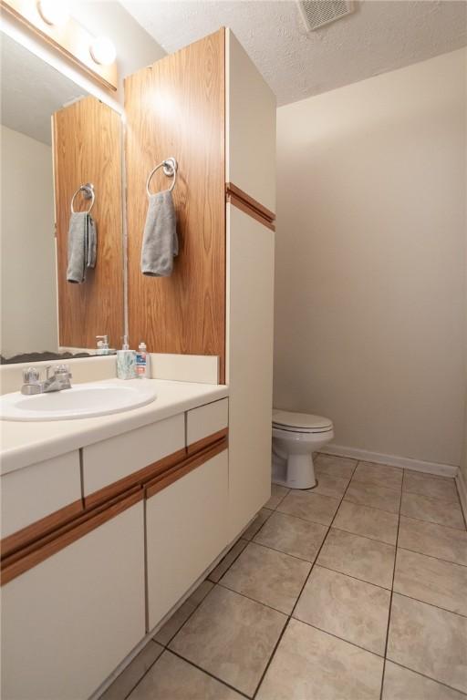 bathroom with visible vents, toilet, tile patterned flooring, a textured ceiling, and vanity