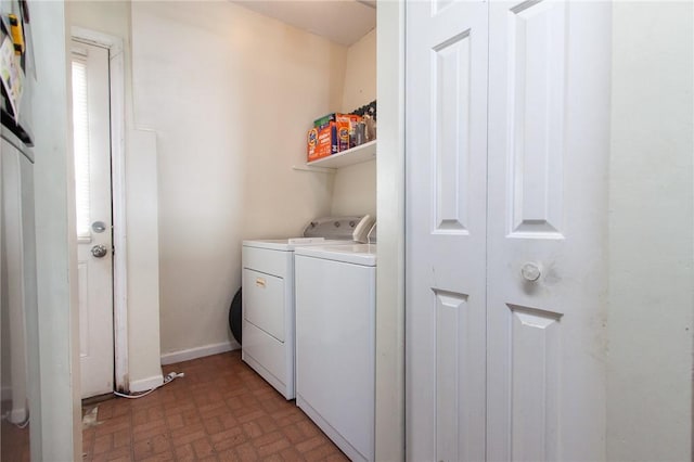 washroom featuring brick floor, laundry area, baseboards, and washer and clothes dryer