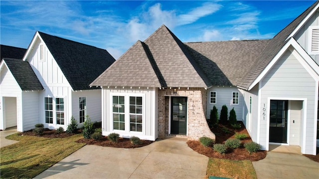 view of front of home featuring brick siding, board and batten siding, and a shingled roof