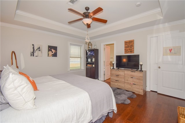 bedroom featuring crown molding, dark wood-type flooring, ceiling fan, and a tray ceiling