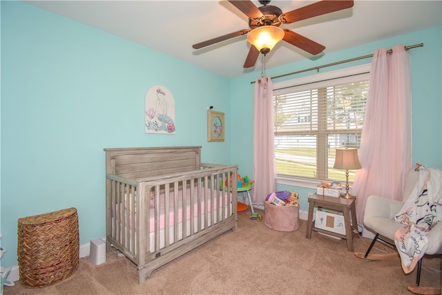 bedroom featuring a crib, ceiling fan, and carpet flooring