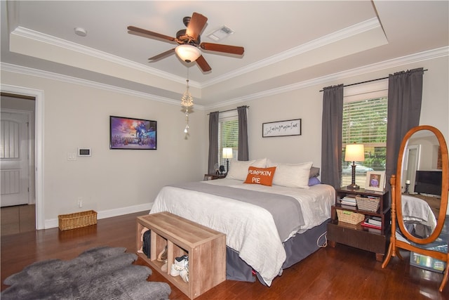 bedroom with dark wood-type flooring, ornamental molding, a tray ceiling, and multiple windows