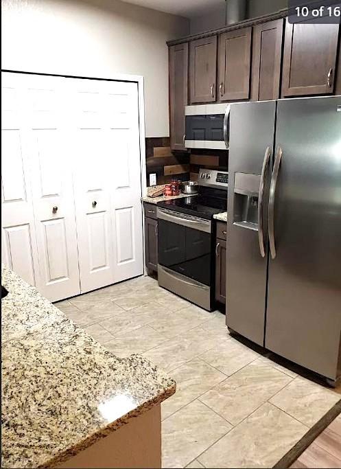 447 W Longleaf Dr Unit 101, Auburn, AL 36832 - kitchen with stainless steel appliances, dark brown cabinets, and light stone countertops