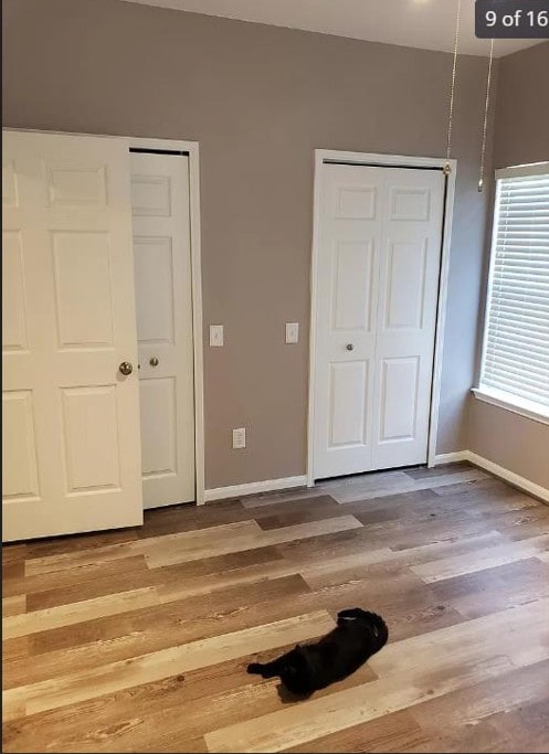 447 W Longleaf Dr Unit 101, Auburn, AL 36832 - unfurnished bedroom featuring wood finished floors and multiple closets