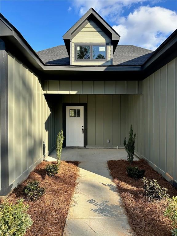 doorway to property with board and batten siding and a shingled roof