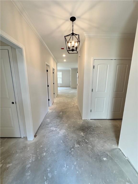 corridor with ornamental molding and a notable chandelier