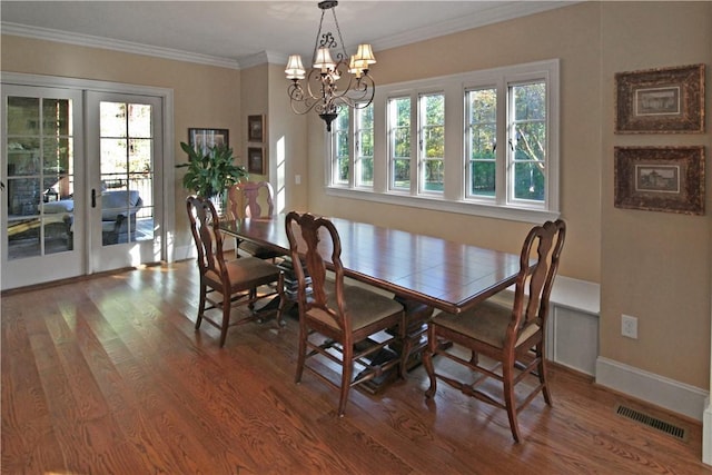 dining room featuring hardwood / wood-style flooring, an inviting chandelier, ornamental molding, and french doors