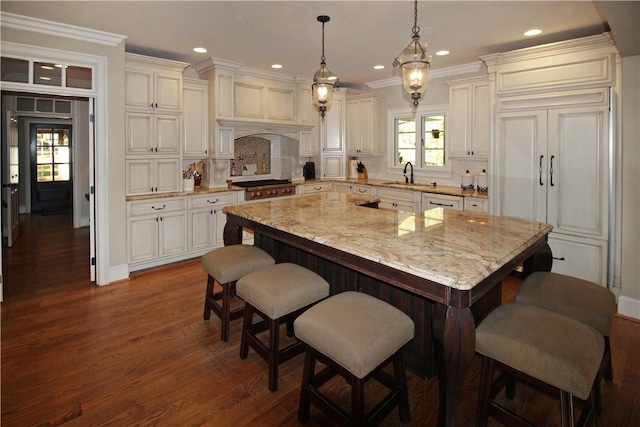 kitchen with decorative backsplash, a center island, light stone countertops, and sink