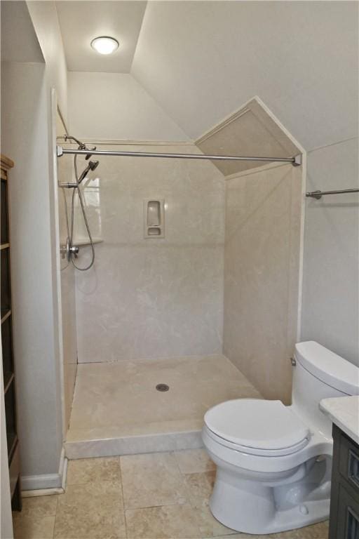 bathroom with tiled shower, vanity, toilet, and lofted ceiling