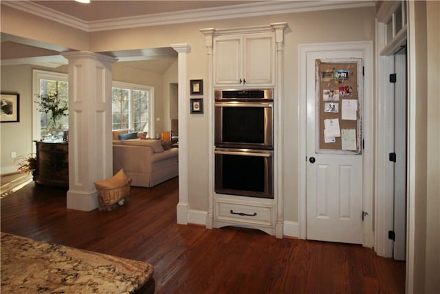 kitchen with decorative columns, light stone counters, double oven, and dark hardwood / wood-style floors