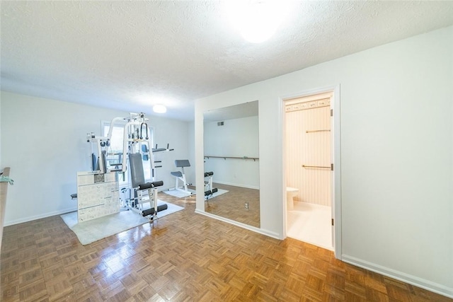 workout area featuring parquet flooring and a textured ceiling