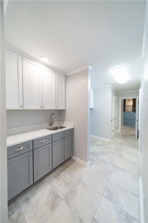 kitchen featuring gray cabinetry, white cabinetry, sink, and ornamental molding