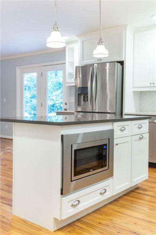 kitchen featuring white cabinets, a kitchen island, hanging light fixtures, and appliances with stainless steel finishes