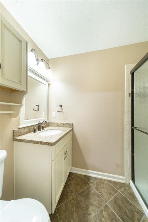 bathroom with tile patterned floors, vanity, a shower with shower door, and toilet