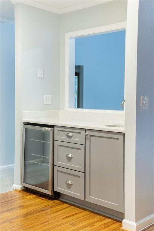 bathroom featuring hardwood / wood-style floors, vanity, crown molding, and beverage cooler