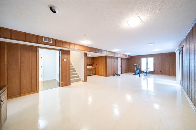 basement featuring a textured ceiling and wooden walls