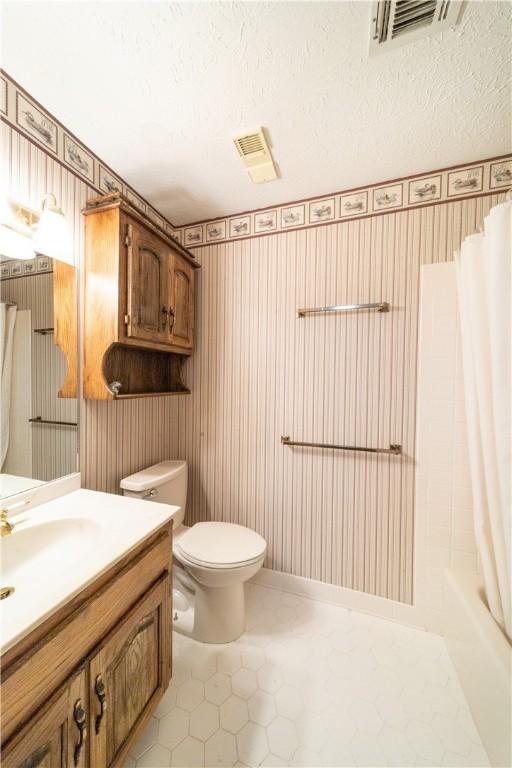 full bathroom with shower / tub combo, vanity, a textured ceiling, and toilet