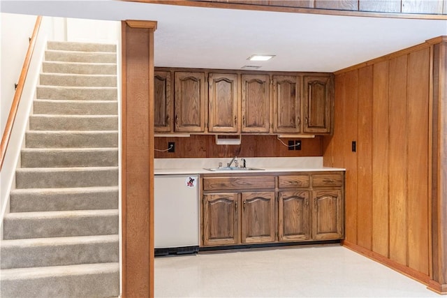 kitchen with dishwasher, wood walls, and sink