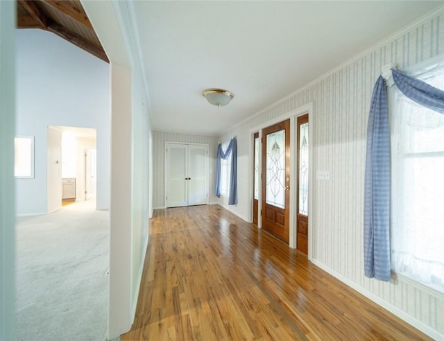 foyer with hardwood / wood-style flooring, vaulted ceiling, and ornamental molding