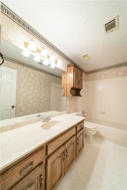 full bathroom with vanity, tile patterned flooring, toilet, a textured ceiling, and shower / bathtub combination