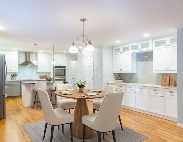 dining area featuring light hardwood / wood-style flooring, crown molding, and a notable chandelier