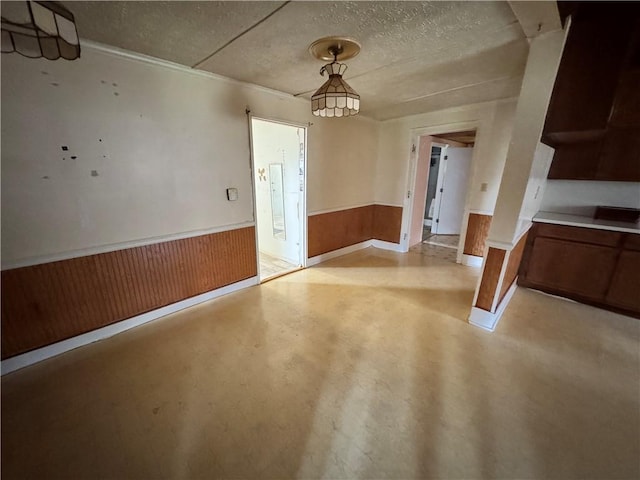 4380 County Road 62, Lafayette, AL 36862 - unfurnished dining area featuring a textured ceiling, wood walls, wainscoting, and finished concrete floors