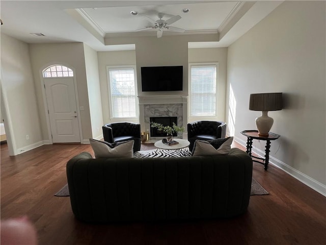 living area with baseboards, a fireplace, crown molding, and wood finished floors