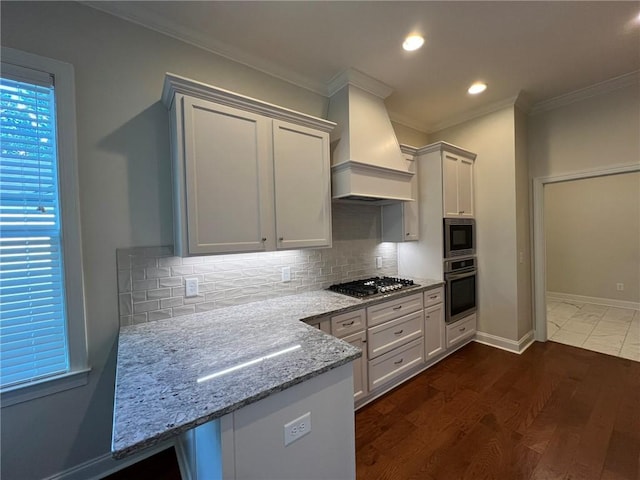kitchen featuring premium range hood, stainless steel appliances, crown molding, decorative backsplash, and light stone countertops