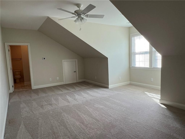 additional living space with lofted ceiling, light carpet, ceiling fan, and baseboards